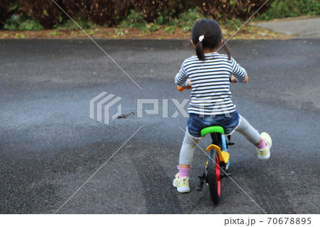 雨上がりにバイクにまたがる女の子の後姿の写真素材