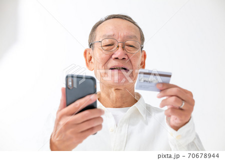 スマートフォンとカードを持つシニア男性 スマートフォンとカードを持つシニア男性 70678944