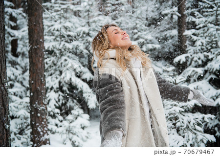 Happy young woman enjoys snowfall in winter outside the city in the forest 70679467