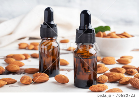 Almond essential oil in dark glass bubbles and fresh almond nuts. Aromatherapy oil natural organic cosmetic. 70680722