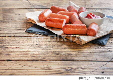 Juicy grilled half meat sausages with tomato sauce and ketchup on a wooden background. Fat fast food. Concept unhealthy eating. Copy space 70680740