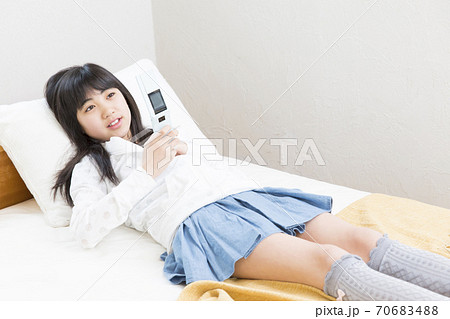 寝転んで携帯メールを見る女の子 70683488