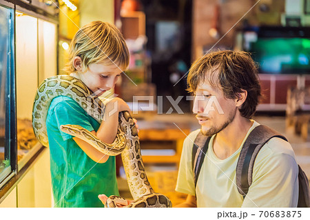 Smiling boy and his father holding python in hands Smiling boy and his father holding python in hands 70683875