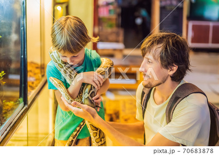 Smiling boy and his father holding python in hands 70683878