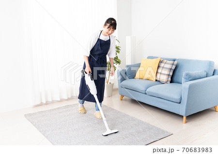 コードレス掃除機でリビングを掃除する若い女性 70683983