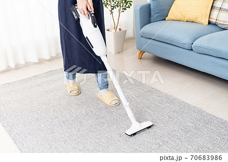 コードレス掃除機でリビングを掃除する若い女性 70683986