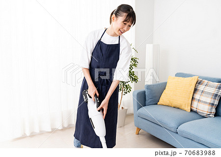 コードレス掃除機でリビングを掃除する若い女性 コードレス掃除機でリビングを掃除する若い女性 70683988