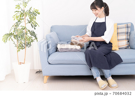 ソファに座って洗濯物をたたむ若い女性 ソファに座って洗濯物をたたむ若い女性 70684032