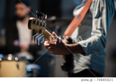 a member of a rock band at a jam session performs a musical part on bass guitar. 70685021