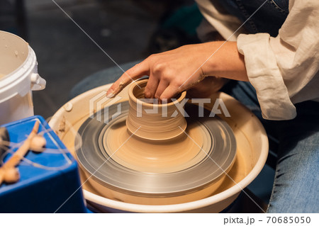 master class on sculpting a pot in an art workshop. the girl behind the potter's wheel makes a blank with her hands. master class on sculpting a pot in an art workshop. the girl behind the potter's wheel makes a blank with her hands. 70685050