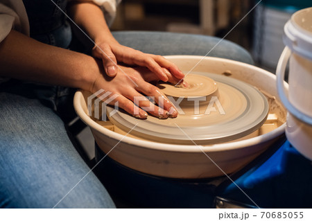 beautiful hands of a young girl, stained with clay when modeling a pot on a potter's wheel in the workshop. beautiful hands of a young girl, stained with clay when modeling a pot on a potter's wheel in the workshop. 70685055