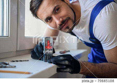 Handyman uses a laser level to measure the distance 70685108