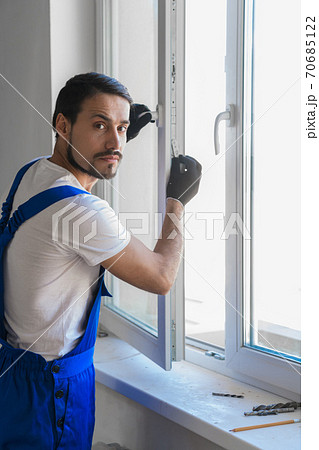 Male artisan installs a window in the room 70685122