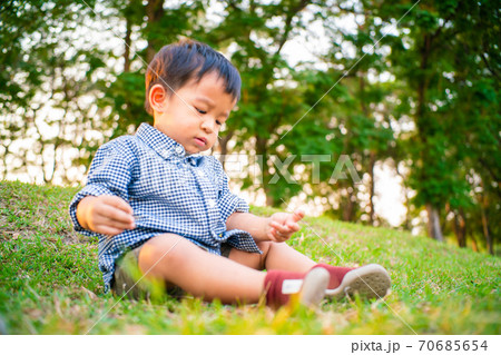 Adorable child boy sitting inder tree playing toy in summer park 70685654