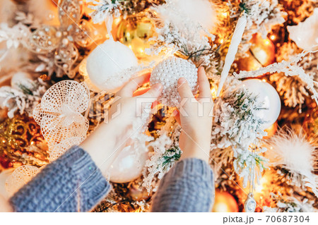 Close up girl hands decorating Christmas tree on Christmas eve at home. Young kid in light bedroom with winter decoration. Christmas New Year december time for celebration concept. Close up girl hands decorating Christmas tree on Christmas eve at home. Young kid in light bedroom with winter decoration. Christmas New Year december time for celebration concept. 70687304