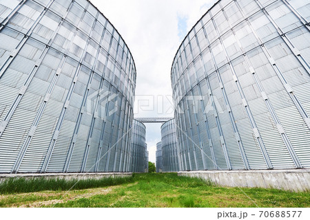 Agricultural Silos. Building Exterior. Storage and drying of grains, wheat, corn, soy, sunflower against the blue sky with white clouds 70688577