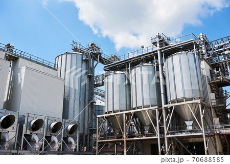 Agricultural Silos. Building Exterior. Storage and drying of grains, wheat, corn, soy, sunflower against the blue sky with white clouds 70688585