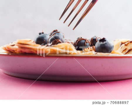 Eating crepes with chocolate and blueberries Eating crepes with chocolate and blueberries 70688897