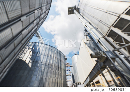 Agricultural Silos. Building Exterior. Storage and drying of grains, wheat, corn, soy, sunflower against the blue sky with white clouds 70689054