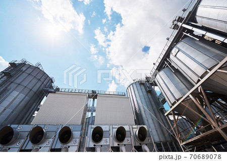 Agricultural Silos. Building Exterior. Storage and drying of grains, wheat, corn, soy, sunflower against the blue sky with white clouds 70689078