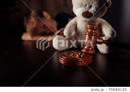 Divorce and separation concept. Wooden gavel, rings and frustrated boy with teddy bear. Family law Divorce and separation concept. Wooden gavel, rings and frustrated boy with teddy bear. Family law 70689130