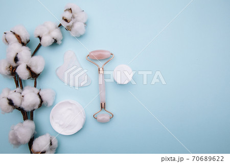 Pink roller face massager and gouache scraper on blue table. Beauty care concept Pink roller face massager and gouache scraper on blue table. Beauty care concept 70689622