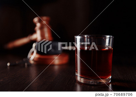Car key, wooden judge gavel and whiskey alcohol drink in a glass on a dark table. Don't drink and drive abstract concept Car key, wooden judge gavel and whiskey alcohol drink in a glass on a dark table. Don't drink and drive abstract concept 70689706