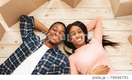 Positive young African American family with carton boxes having rest on moving day, overhead view 70690791