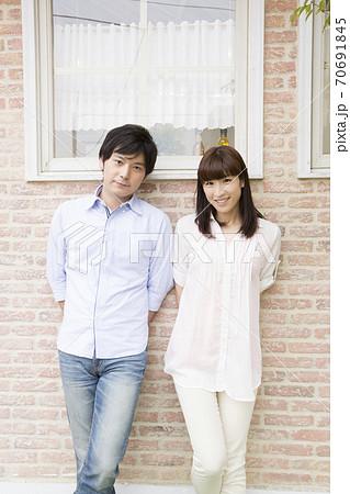壁の前に立つ男女の写真素材