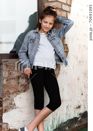 portrait of a beautiful teenage girl posing against a brick wall and window 70691995