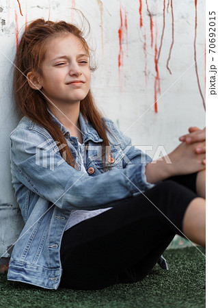 portrait of a beautiful teenage girl posing against a brick wall 70692015