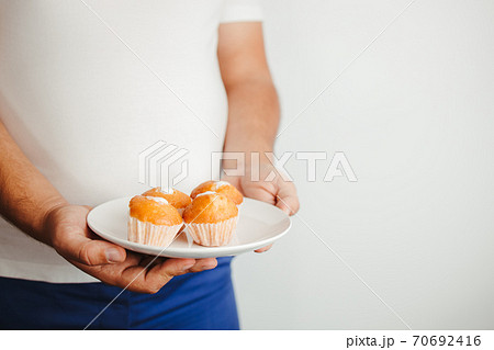 Overweight man eating unhealthy sweet cupcakes Overweight man eating unhealthy sweet cupcakes 70692416