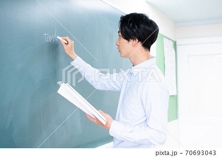 黒板に数式を書く若い男性教師の写真素材