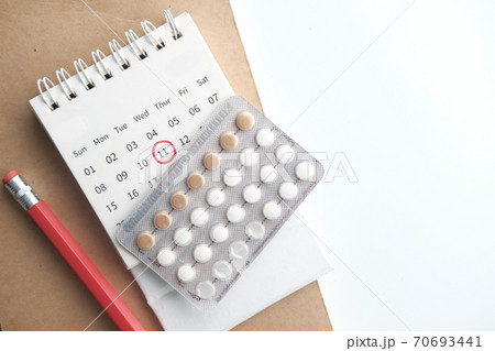 birth control pills , calendar and notepad on table  70693441