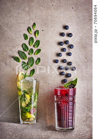 Two summer cocktails at concrete grey background. mohito and blueberry tea. Fresh cold drinks Two summer cocktails at concrete grey background. mohito and blueberry tea. Fresh cold drinks 70694064