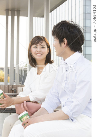 ベンチに座って会話するカップル ベンチに座って会話するカップル 70694103