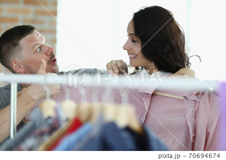 Man and woman are smiling at each other next to hanger with things 70694674