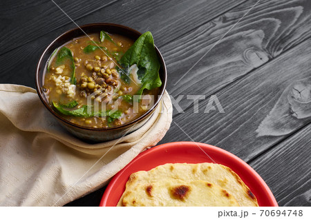 Spinach Mung Dhal and Chapati on black wooden table top. Moong Dal - Indian Cuisine curry. 70694748