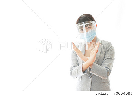 バツサインをするフェイスシールドを装着したビジネスウーマン バツサインをするフェイスシールドを装着したビジネスウーマン 70694989