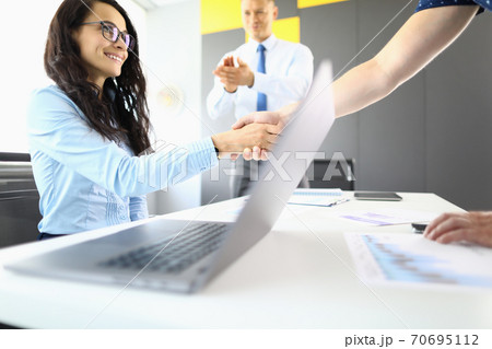Businesswoman and partners in office shake hands and smil 70695112