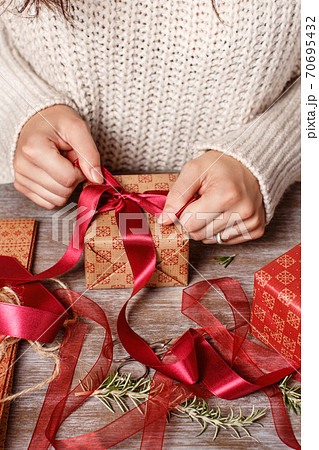 Woman ties a ribbon bow and wrapping presents 70695432
