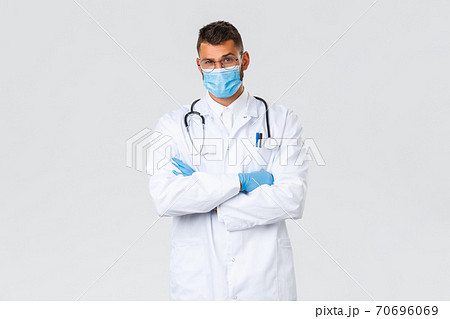 Covid-19, healthcare workers, pandemic and preventing virus concept. Doubtful and suspicious male doctor in scrubs and medical mask dont believe patient, raise eyebrow disbelief 70696069
