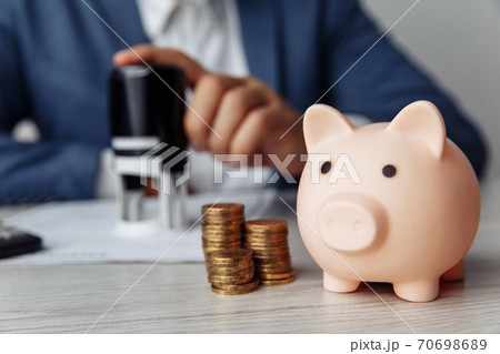 Pink piggy bank with stack of coins on desk in office. Save money and management financial concept Pink piggy bank with stack of coins on desk in office. Save money and management financial concept 70698689
