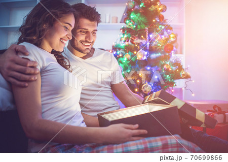 The happy man and a woman open the light box near the christmas tree The happy man and a woman open the light box near the christmas tree 70699866