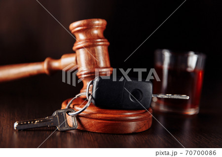 Car key, judge gavel and bottle of alcohol with glass close-up. Drunk driving concept 70700086