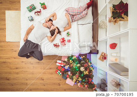 The kissing couple lay on the bed with gifts. view from above The kissing couple lay on the bed with gifts. view from above 70700195