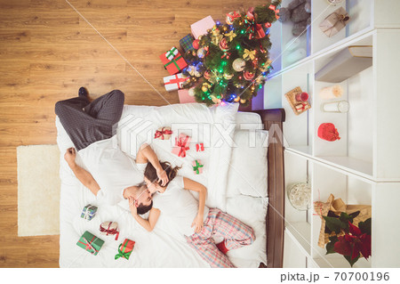 The kissing couple lay on the bed with gifts. view from above The kissing couple lay on the bed with gifts. view from above 70700196