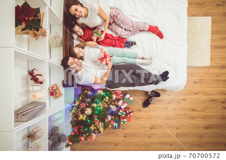 The happy family lay on the bed near a christmas tree. view from above The happy family lay on the bed near a christmas tree. view from above 70700572
