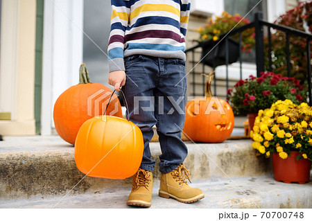 Little boy at halloween party. Child holds a bucket shaped like a halloween pumpkin jack o lantern.  70700748