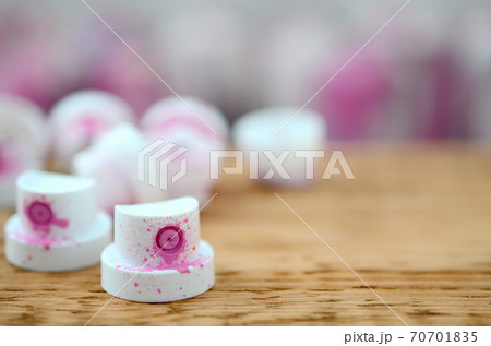 The soiled pink nozzles from the paint sprayer lies on a wooden plank on a background of a many dirty spray cans 70701835
